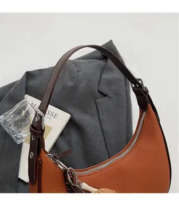 Detailansicht der braunen Litschi-Lederstruktur und Konstruktion der Hobo-Tasche