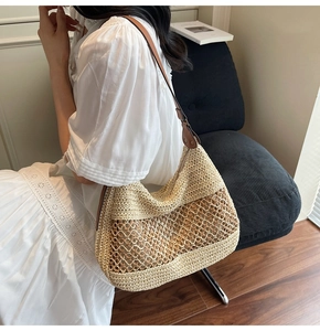 Detail of woven straw shoulder bag with brown leather strap worn with white dress