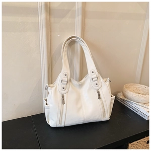 Détail d'un sac cabas blanc avec fermetures éclair décoratives et poches sur les côtés