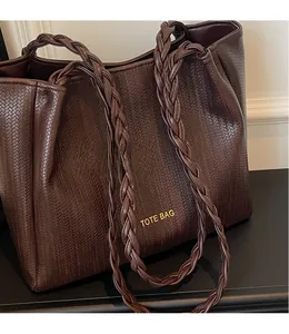 Detail of dark brown woven tote bag with smooth shoulder straps and gold lettering