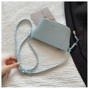 Detail of light blue crossbody bag with lychee texture and silver metal ball charm