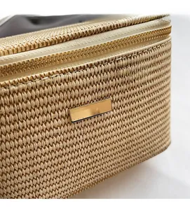 Detailansicht der beige gewebten Handtasche mit goldenem Reißverschluss und Dekoplatte