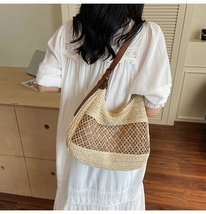 Detail of hollow woven straw hobo bag with adjustable brown leather shoulder strap