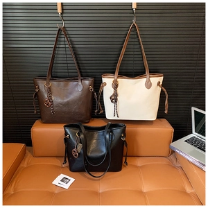 Three large tote bags in brown, cream, and black leather shown in an urban office setting