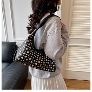 Seitenansicht der schwarzen Schultertasche mit silbernen Nieten auf glattem Kunstleder