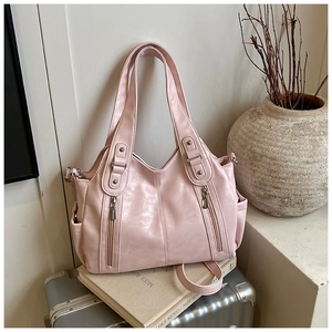 Détail d'un grand sac fourre-tout rose clair avec doubles zips posé sur une valise