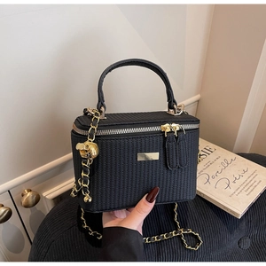 Detail der schwarzen gewebten Tasche mit goldenem Totenkopf-Anhänger und Kettengurt
