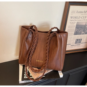 Close-up of brown tote bag with woven texture and braided handle details