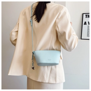 Detail of light blue lychee pattern leather bag with metal ball charm and shoulder strap