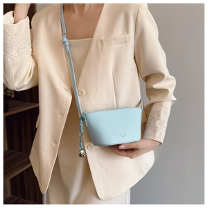 Close-up of mint blue mini bucket bag with lychee grain texture and heart charm