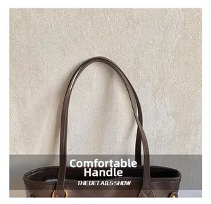 Detail view of brown leather bag handle with golden metal rings and fine stitching