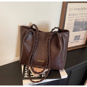 Close-up of dark brown woven tote bag with double braided handles and printed text detail