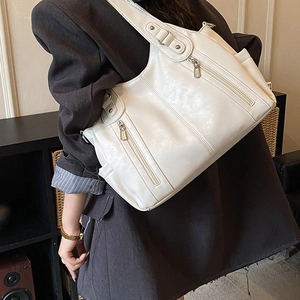 Vue latérale d'un grand sac cabas en cuir blanc porté par un mannequin pour un look chic