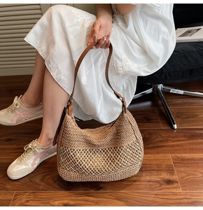 Detail of woven straw shoulder bag with leather strap and white mesh texture overlay