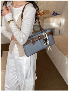 Détail du sac bandoulière en denim bleu avec lanières en cuir brun et pendentif