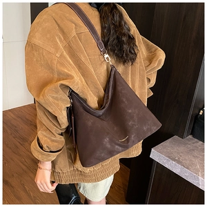 Detail view of a large brown suede hobo bag with smooth leather strap and gold metal hooks