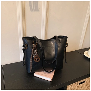 Detail of black faux leather tote bag with creative knot charm and drawstring tassels