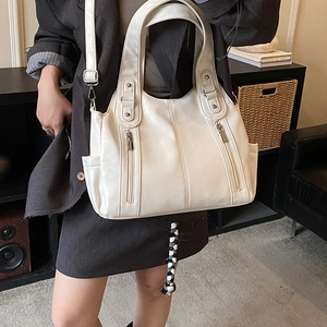 Détail d'un grand sac cabas crème avec poches zippées métalliques et bandoulière réglable