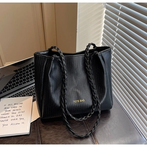 Detail of black woven tote bag with braided handles and TOTE BAG lettering text