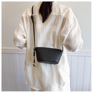 Chic black crescent crossbody bag with lychee texture and silver moon charm on model