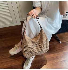 Detail of hand-woven straw tote bag with brown leather straps and cutout crochet texture