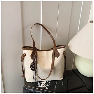 Close-up of cream tote bag with dark brown handles and elegant brand embossing