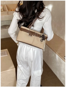 Détail du sac à main rétro en toile kaki et cuir marron porté à l'épaule par le mannequin