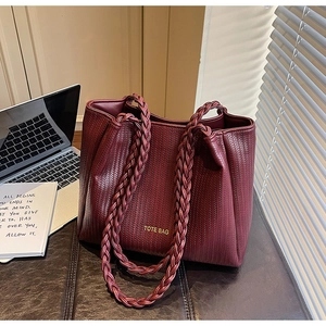 Detail of burgundy woven tote bag with gold lettering on premium synthetic leather