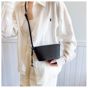 Detail of black pebbled leather crossbody bag with silver heart pendant and brand logo
