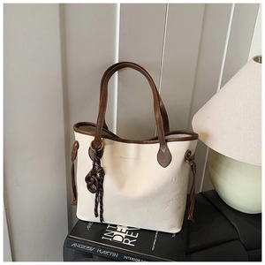 Detail view of cream tote bag with contrast brown trim and embossed brand logo