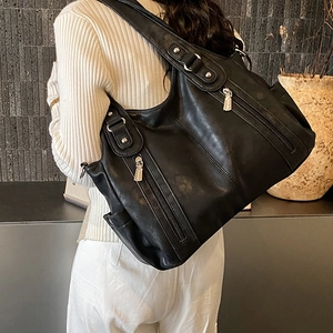Vue détaillée du grand sac cabas noir avec fermetures éclair argentées porté par le mannequin