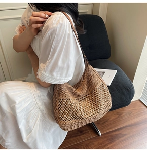 Detail showing the brown woven straw texture and hollow mesh design of the shoulder bag