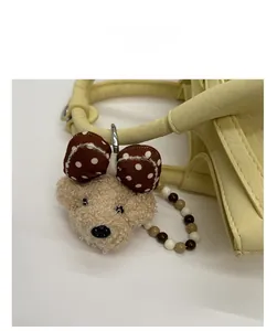 Nahaufnahme eines Teddybär-Anhängers mit gepunkteter Schleife an einer Handtasche