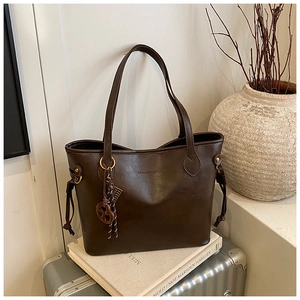 Detailed view of deep brown leather tote bag with gold hardware and side drawstrings