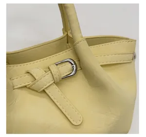 Details der Silberschnalle und Ziernähte an der hellgelben Leder-Beuteltasche