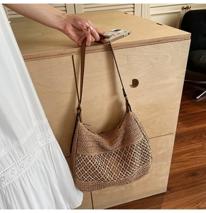Detail of hand-woven straw shoulder bag with white wave mesh trim and dark leather strap