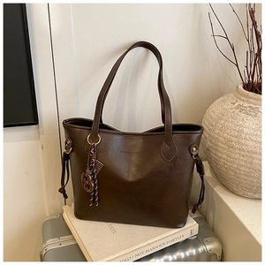 Detail of dark brown tote bag featuring brand logo, thin straps and decorative drawstrings