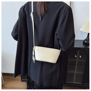 Close-up of cream pebble leather crossbody bag with knot detail on black blazer
