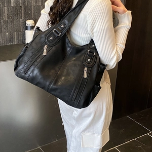 Détail d'un grand sac cabas noir en simili cuir avec poches zippées et larges bandoulières