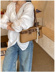 Détail du sac à bandoulière vintage en toile marron avec boucle en cuir et pendentif tissé