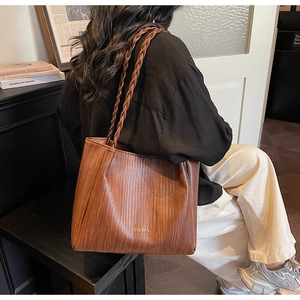 Close-up of woven texture on brown PU leather tote bag with braided shoulder straps