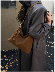 Detail view of caramel brown suede hobo bag with gold hooks and Ginkgo leaf background