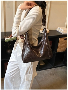 Borsa hobo vintage in pelle marrone scuro indossata da una modella in un interno moderno
