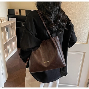 Detail of retro dark brown woven tote bag featuring braided straps and gold text