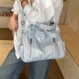Détail du sac cabas bleu clair avec fermetures éclair argentées et bandoulière réglable