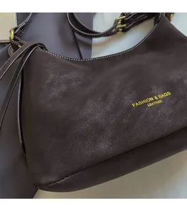 Gros plan d'un sac en cuir marron foncé grainé avec boucle en métal et lettrage vintage