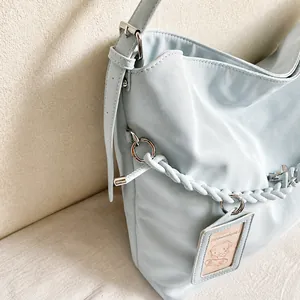 Close-up of silver metal ring buckle and stylish braided rope on light blue tote bag