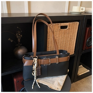 Détail d'un sac cabas noir vintage avec anses marron dans un décor d'intérieur