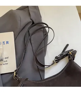 Détail du sac sous le bras en cuir marron foncé avec bandoulière réglable et boucle dorée