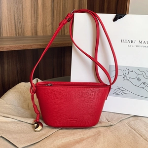 Red litchi grain leather crossbody bag with silver heart pendant and knotted shoulder strap
